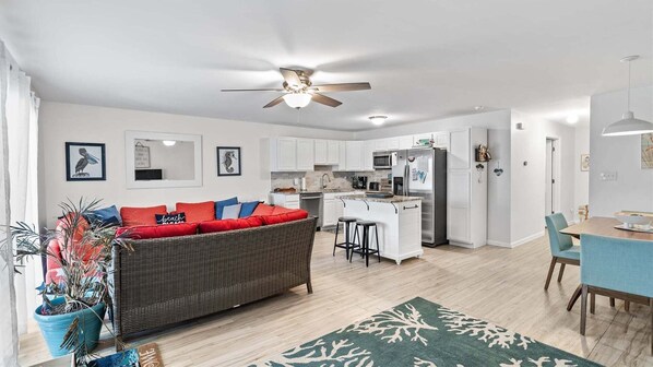 Eine moderne Wohnung mit Küchenzeile, Essbereich und Wohnzimmer mit Sofa und Deckenventilator.