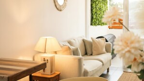 Ein gemütliches Wohnzimmer mit einer Couch, einer Lampe, einem Holztisch und einem Spiegel an der Wand.