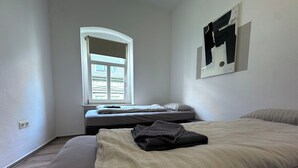 Un dormitorio con cama, ventana y un cuadro colgado en la pared.
