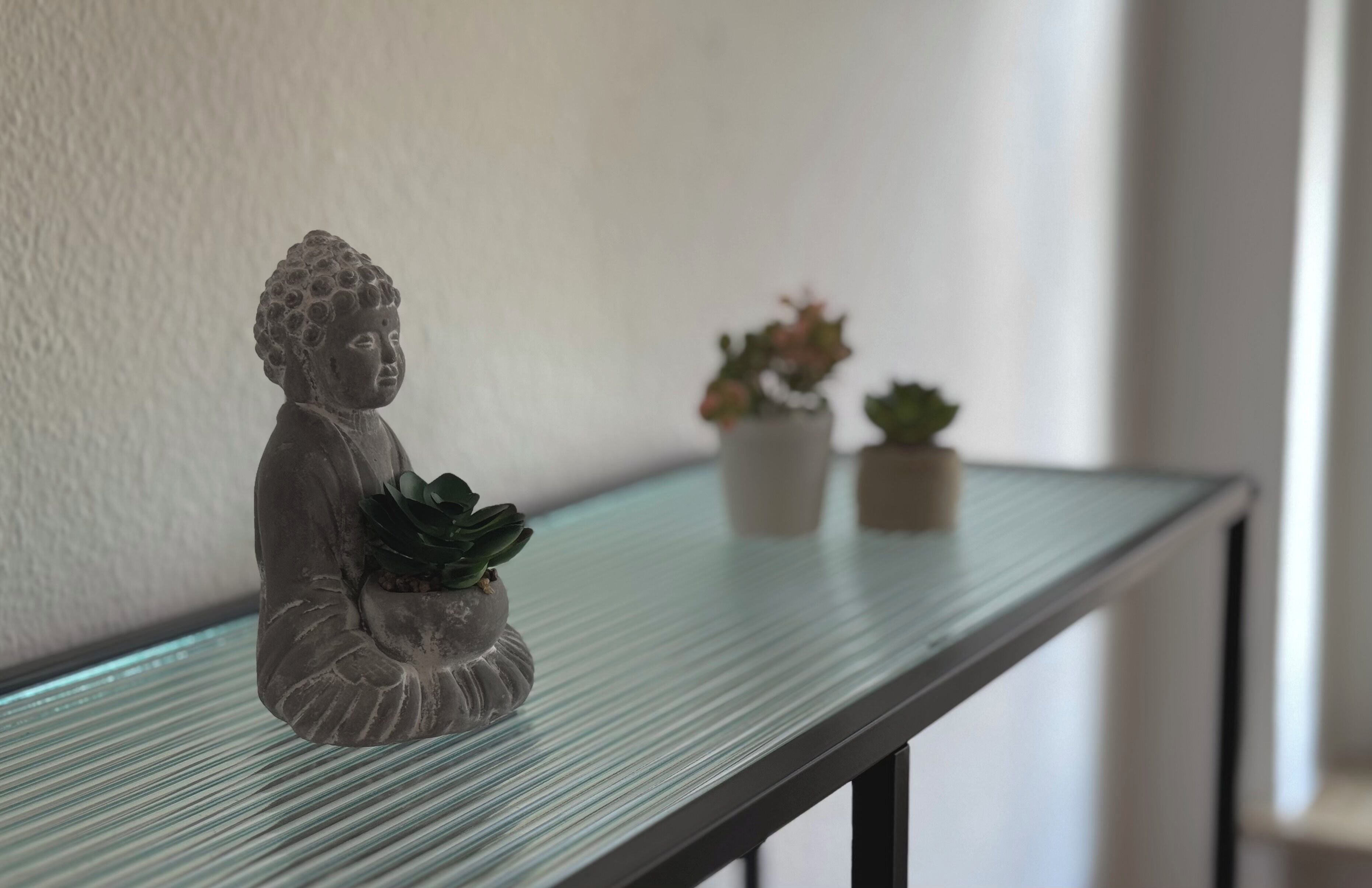 A statue of a seated figure with a plant on a glass railing.