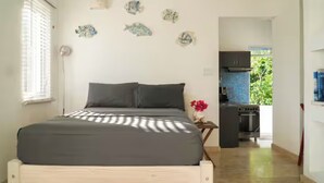 Un dormitorio con una cama, una ventana, una pared decorada con peces y vistas a una cocina y zona exterior.