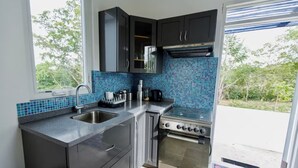 Una cocina moderna con gabinetes oscuros, un lavamanos de acero inoxidable y un horno empotrado.