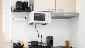 Une petite cuisine équip ée d’un four à micro-ondes, d’un grille-pain et d’une machine à café.