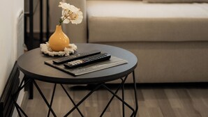 Un salon avec une table basse ronde noire, un canapé beige et un vase jaune contenant des fleurs blanches.