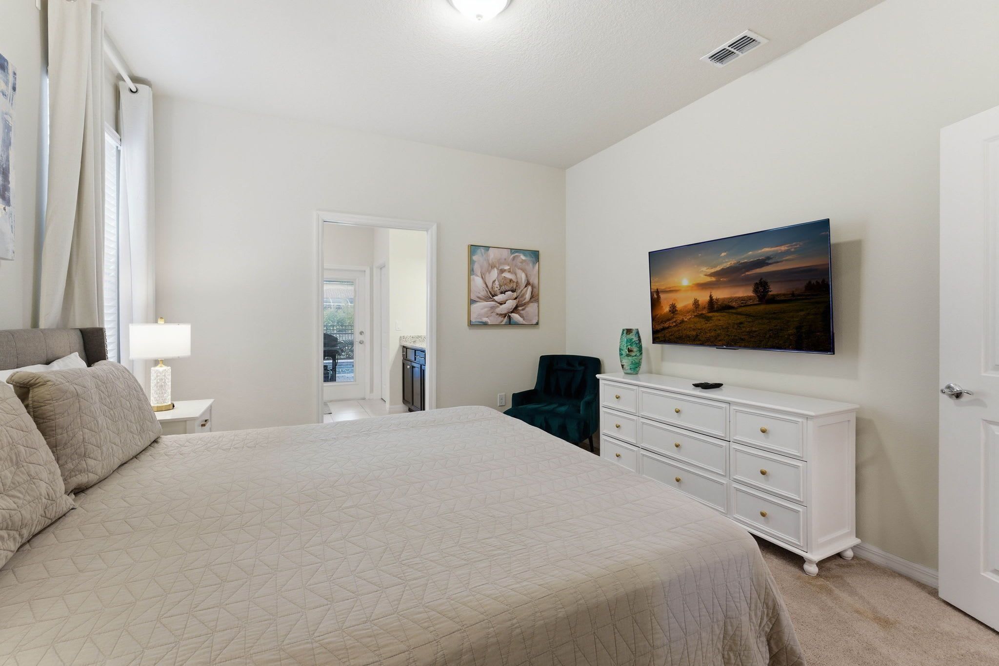 A bedroom with a large bed, a dresser, a chair, and a painting on the wall.