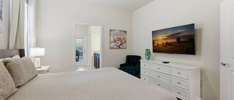 A bedroom with a large bed, a dresser, a chair, and a painting on the wall.