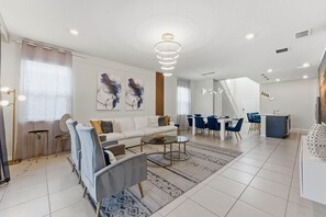 Un salon moderne comprenant un canapé, une table basse et un coin repas avec des chaises et une table.