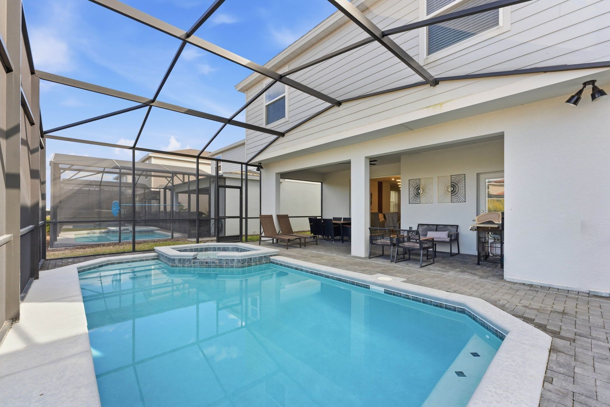 A swimming pool with a glass enclosure, surrounded by lounge chairs and a patio area.