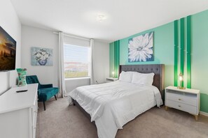 Ein Schlafzimmer mit einem großen Bett, einem Nachttisch, einer Kommode, einem Sessel und einem Bild an der Wand.