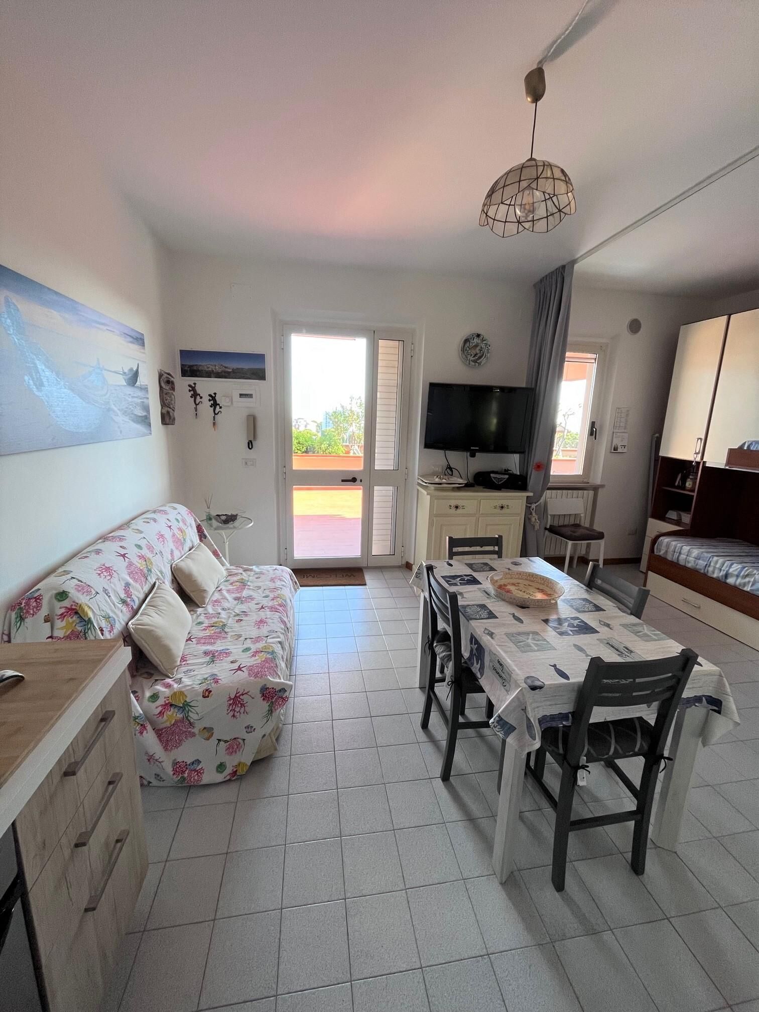 A compact living space with a sofa, dining table, and TV.