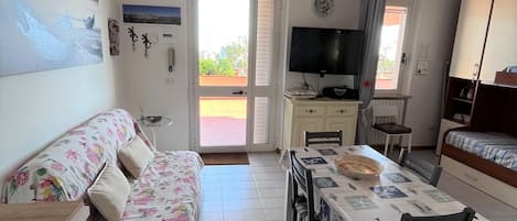 Un espacio habitable compacto con sofá, mesa de comedor y televisor.