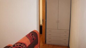 Huoneessa on vaatekaappi, ovi ja kuviollinen kangas lattialla.