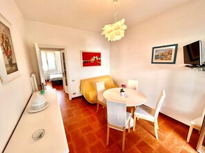 A cozy dining area with a round table and chairs, a sofa, and a hanging light fixture. - Three-room apartment with sea and beach view (Marcelli)