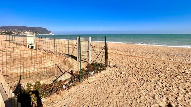 Platja amb una xarxa de voleibol i una torre de socorristes.