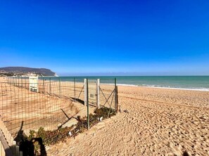 A beach with a volleyball net and a lifeguard tower. - Three-room apartment with sea and beach view (Marcelli)