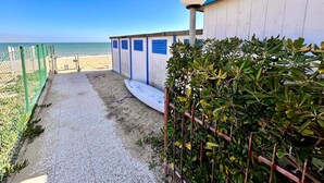 Un camí que porta a cabanes de platja amb vista al mar.
