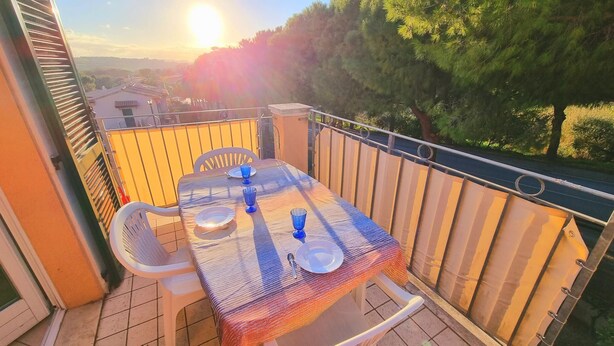 A balcony with a table set for two, chairs, and a view of the surrounding area. - Two-room Caesar [center, park, terrace] (Sirolo)