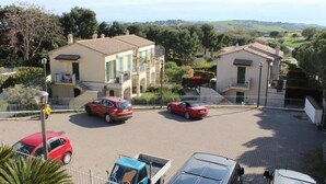 A residential area with two buildings, a parking lot with several cars, and a view of the countryside. - Two-room Caesar [center, park, terrace] (Sirolo)