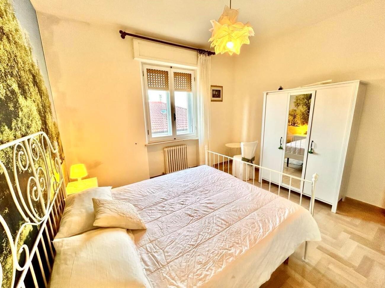 A bedroom with a bed, a wardrobe, a window, and a chair.