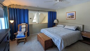 A bedroom with a bed, a wooden bench, a chair, a desk, a lamp, a ceiling fan, and a framed picture on the wall. - Tenney Mountain Ski Resort Condo (Plymouth)