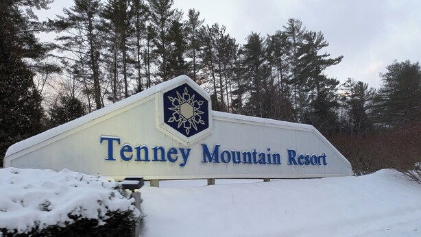 A sign for Tenney Mountain Resort with a snow-covered ground and trees in the background. - Tenney Mountain Ski Resort Condo (Plymouth)