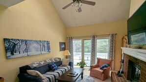A living room with a sofa, armchairs, a coffee table, a fireplace, and a ceiling fan. - Tenney Mountain Ski Resort Condo (Plymouth)