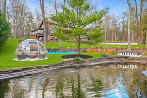 Ein Haus mit Schwimmbad, Teich und Gartenmöbeln.