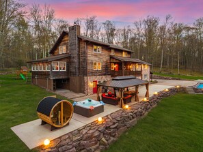 Una cabaña de troncos con jacuzzi, mobiliario exterior y una pared de piedra.