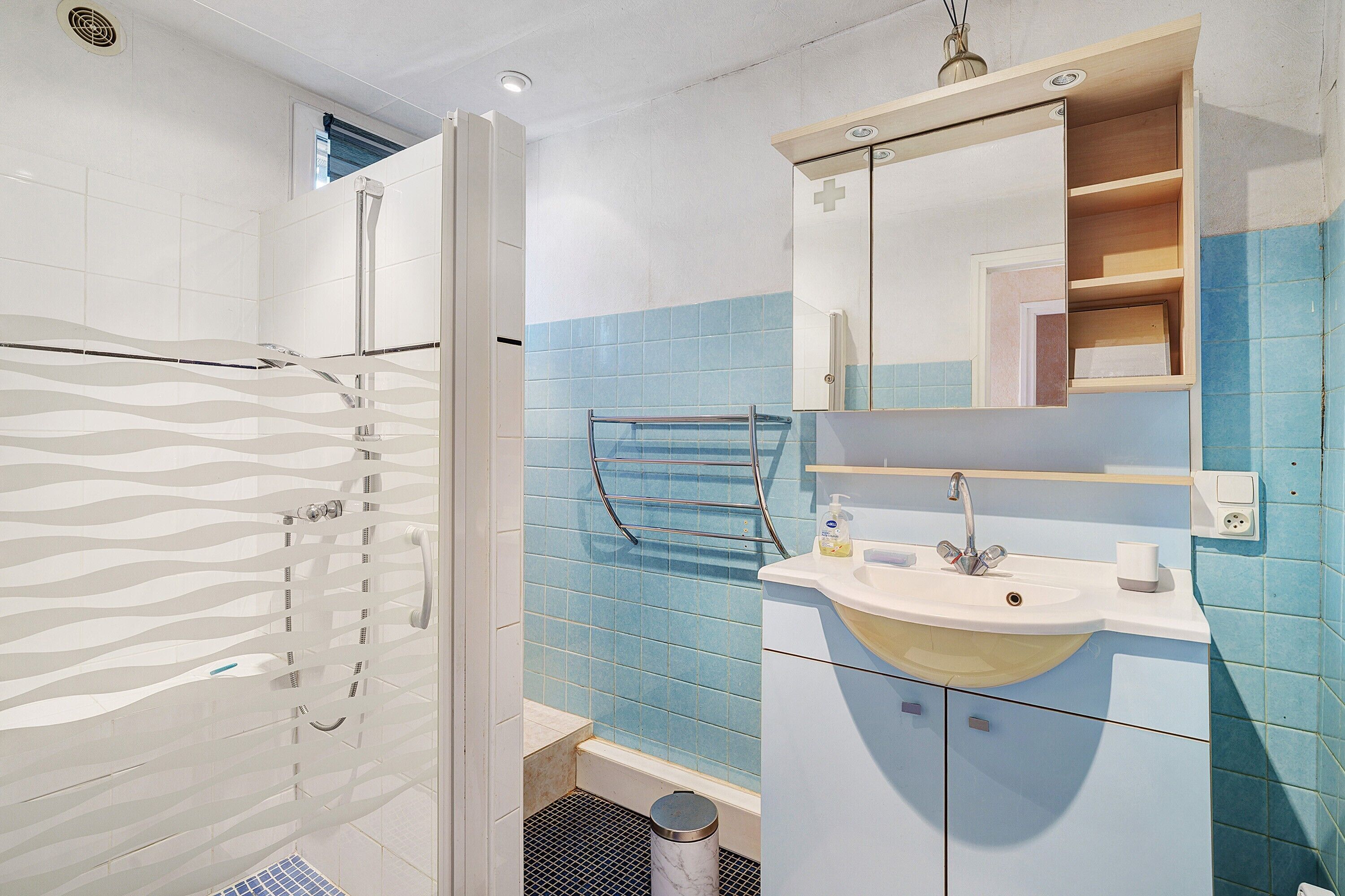 Ein Badezimmer mit Dusche, Waschbecken, Spiegel und gefliesten Wänden.