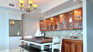 Un comedor con una mesa, sillas, una araña y armarios de madera con puertas de cristal.