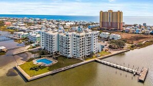 Zona residencial costera con un gran edificio de apartamentos, una piscina y un puerto deportivo.