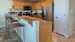Una cocina con armarios de madera, un refrigerador de acero inoxidable, un microondas y una encimera de granito.
