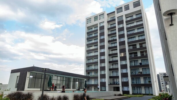 A modern building with a large glass facade, a rooftop pool, and a well-maintained garden area. - Koriwo Haven- Your Home Away From Home in Nairobi (Syokimau)