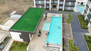 A rooftop swimming pool with a green roof, surrounded by a landscaped area with pathways and a small garden. - Koriwo Haven- Your Home Away From Home in Nairobi (Syokimau)