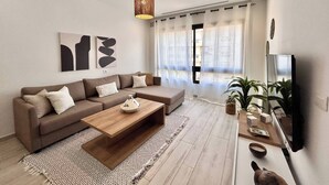 A modern living room with a sectional sofa, a wooden coffee table, and a flat-screen TV. - Malachite Elegance & Comfort in Sidi Daoud (La Marsa)