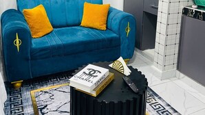 Un soggiorno moderno con un divano blu, cuscini gialli e un tavolino da caffè nero con libri.