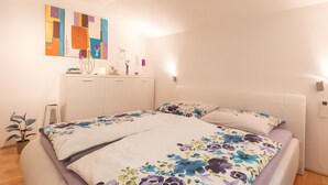 A bedroom with a bed, a wardrobe, a desk, and a wall art piece. - Apartment "For 2 People, 65 m²" with Mountain View, Wi-Fi, and Air Conditioning (Scheffau am Tennengebirge)
