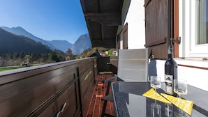 A balcony with a table, a bottle, and glasses, overlooking a mountainous landscape. - Apartment "For 2 People, 65 m²" with Mountain View, Wi-Fi, and Air Conditioning (Scheffau am Tennengebirge)
