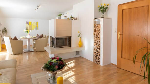 A modern living room with a sofa, a dining table, a TV, a vase with flowers, and a wooden door. - Apartment "For 2 People, 65 m²" with Mountain View, Wi-Fi, and Air Conditioning (Scheffau am Tennengebirge)