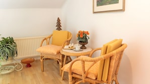 A room with two wicker chairs, a small round table with a vase of flowers, a book, and a cup. - Apartment "For 2 People, 65 m²" with Mountain View, Wi-Fi, and Air Conditioning (Scheffau am Tennengebirge)