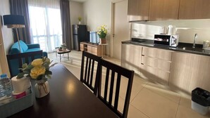 A modern kitchen with wooden cabinets, a dining table with chairs, a refrigerator, and a coffee maker. - High Floor Sea View 2 Bed Room (Pattaya)