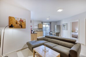 A modern living room with a sectional sofa, a wooden coffee table, and a painting on the wall. - Modern and cosy 2 bedroom flat with balcony BSAI1-1 (Swieqi)