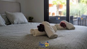 A neatly made bed with patterned bedding, a small potted plant, and a view of the outdoors through a glass door. - Chic 2 bedroom Apartment with Comunal Pool VM75 (Villamartín)