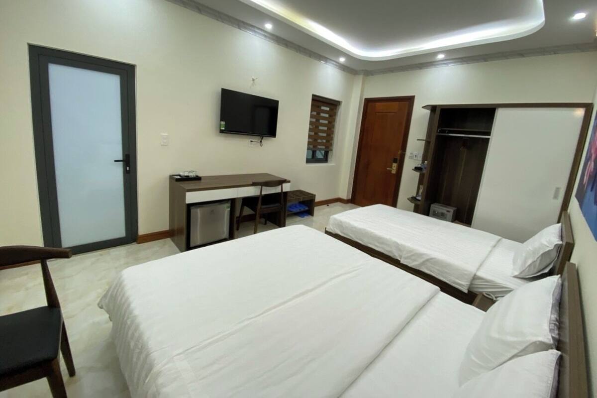 A hotel room with two beds, a desk, a TV, and a wardrobe.