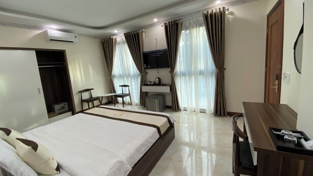 Une chambre d’hôtel avec un grand lit, un bureau, une chaise, une télévision et une kitchenette.