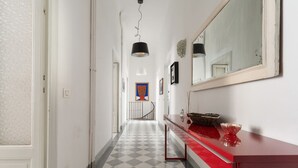 Un pasillo con suelo a cuadros, un mostrador rojo con espejo y una escalera al fondo.