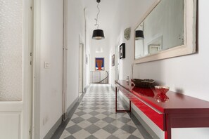 Ein Flur mit Schachbrettmuster, einer roten Theke mit Spiegel und einer Treppe im Hintergrund.