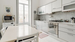 Una cocina moderna con armarios blancos, estufa a gas, microondas y un lavamanos.