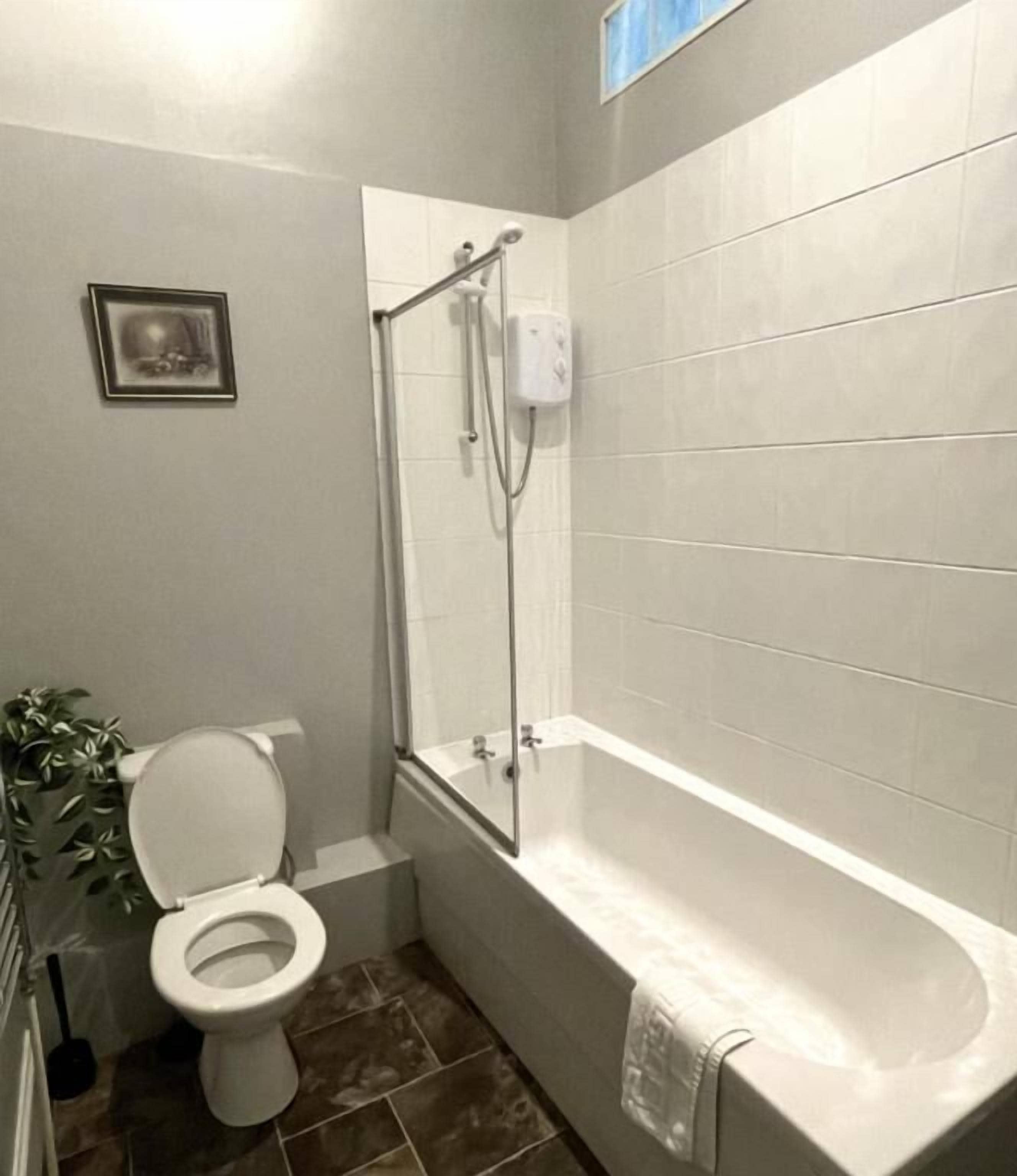 Une salle de bain avec des toilettes, une douche et une baignoire.