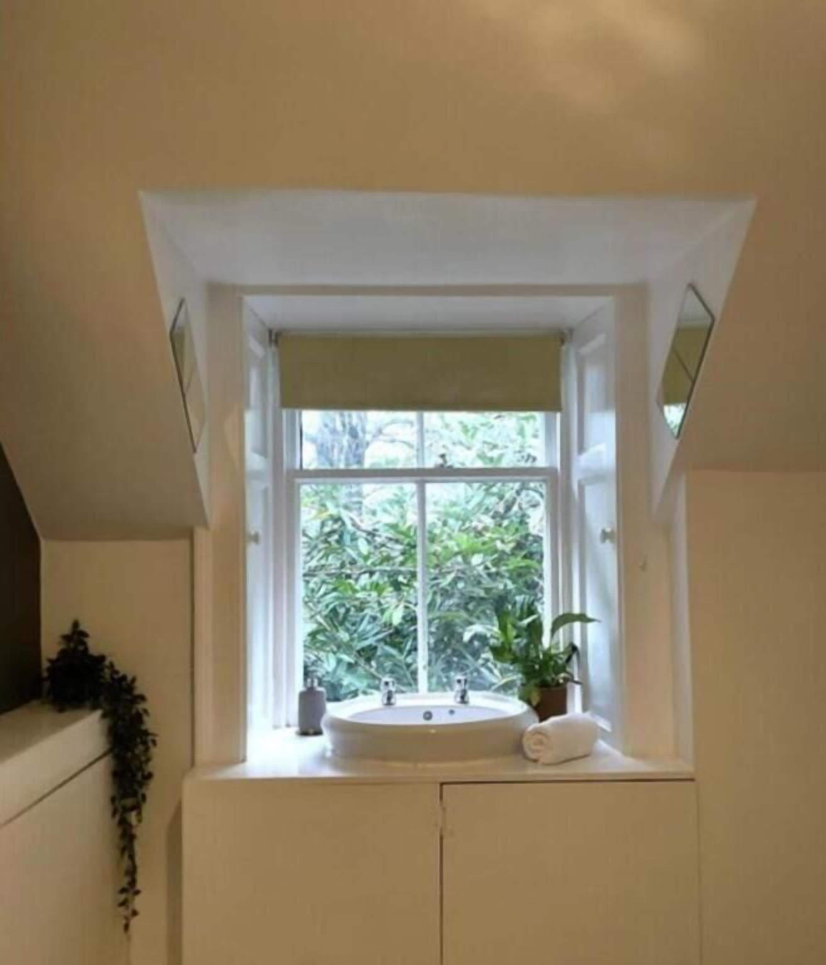 A bathroom with a window, a sink, and a towel.